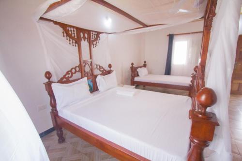 a bedroom with two beds with white sheets at Havillah Gardens Watamu in Watamu