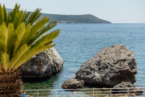 a person standing next to two large rocks in the water at Swisslion Studios in Herceg-Novi