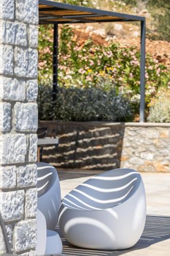 two white chairs sitting next to a stone wall at Seafront elegant villas, with infinity pools & devine views! in Agios Pavlos