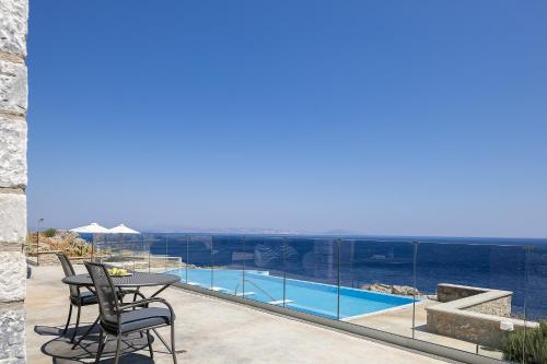 a balcony with a table and chairs and a view of the ocean at Seafront elegant villas, with infinity pools & devine views! in Agios Pavlos