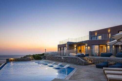 a villa with a swimming pool and a house at Seafront elegant villas, with infinity pools & devine views! in Agios Pavlos