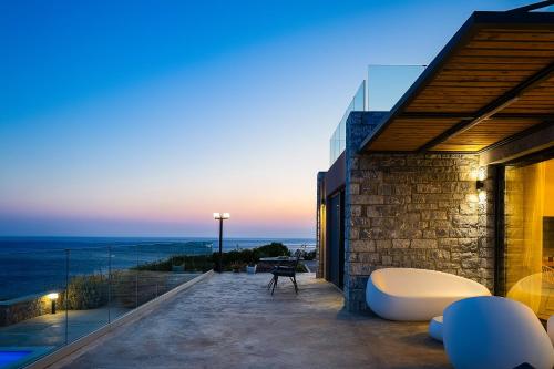 a house with a balcony with a view of the ocean at Seafront elegant villas, with infinity pools & devine views! in Agios Pavlos
