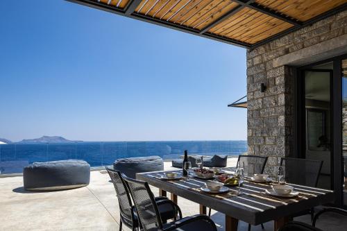 a wooden table with chairs on a patio at Seafront elegant villas, with infinity pools & devine views! in Agios Pavlos