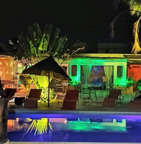 a pool with chairs and an umbrella at night at Riad côté jardin in Saly Portudal