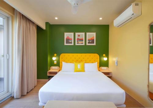 a bedroom with a white bed with a green wall at Bloom Boutique - Rishikesh Hills in Rishīkesh