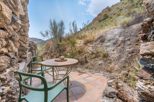 a table and chairs on a patio with a mountain at Off-Grid - Puerto Mika in Órgiva