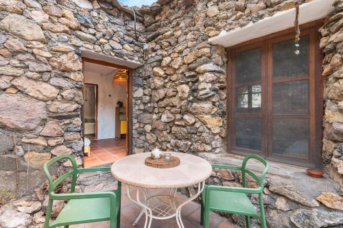a table and chairs on a patio with a stone wall at Off-Grid - Puerto Mika in Órgiva