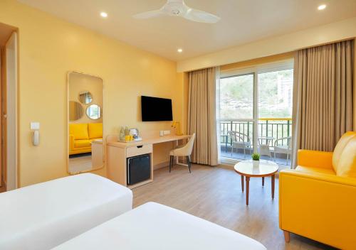 a hotel room with a bed and a desk and a television at Bloom Boutique - Rishikesh Hills in Rishīkesh