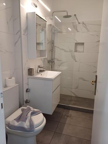 a white bathroom with a sink and a toilet at LITO STUDIOS APARTMENTS in Pythagoreio