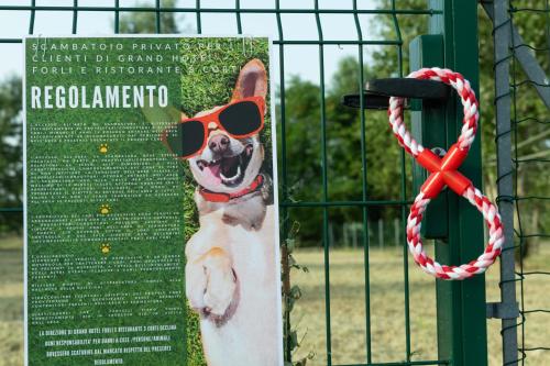 a sign with a dog wearing sunglasses and a red ribbon at Grand Hotel Forlì in Forlì