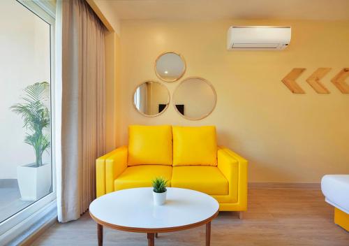 a yellow couch in a living room with a table at Bloom Boutique - Rishikesh Hills in Rishīkesh
