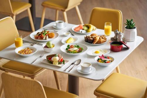 a table with plates of breakfast foods on it at Courtyard by Marriott Pyeongtaek in Pyeongtaek