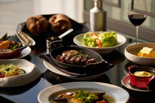 a table with plates of food and a glass of wine at Courtyard by Marriott Pyeongtaek in Pyeongtaek