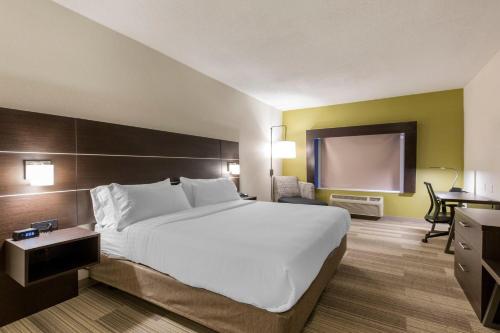 a hotel room with a large bed and a projection screen at Holiday Inn Express & Suites Chicago West - St Charles by IHG in Saint Charles