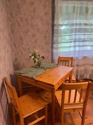 a wooden table with a vase of flowers on it at Lauku viesu māja Bajāri in Rucava