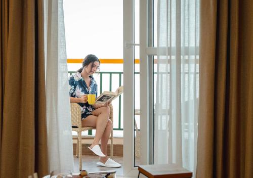 a woman sitting in a chair reading a book at Bloom Boutique - Rishikesh Hills in Rishīkesh