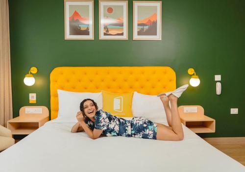 a woman laying on a bed talking on a phone at Bloom Boutique - Rishikesh Hills in Rishīkesh