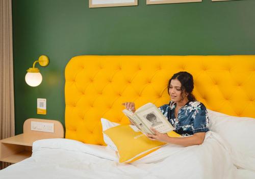 a woman laying in bed reading a book at Bloom Boutique - Rishikesh Hills in Rishīkesh