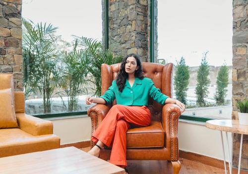 a woman sitting in a chair in a window at Bloom Boutique - Rishikesh Hills in Rishīkesh