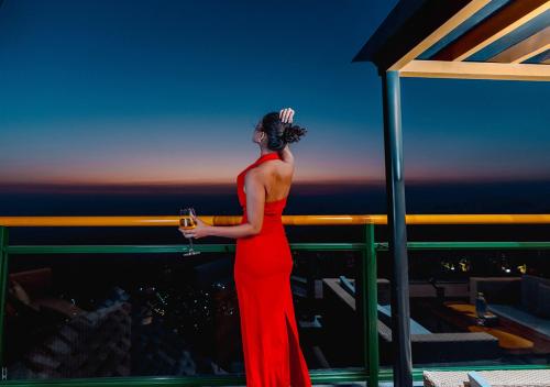 a woman in a red dress standing on a balcony at Bloom Boutique - Rishikesh Hills in Rishīkesh