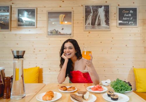 a woman sitting at a table with a glass of orange juice at Bloom Boutique - Rishikesh Hills in Rishīkesh