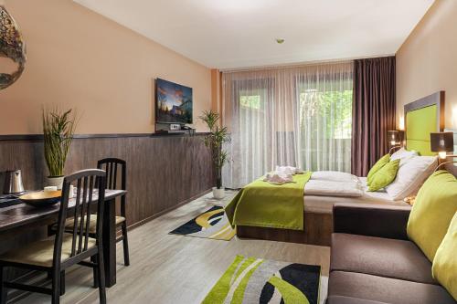 a bedroom with a bed and a table and a desk at Park Hotel Bükfürdő in Bük