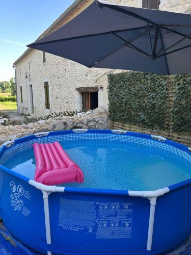 une piscine avec deux chaises et un parasol dans l'établissement Poitevins, à Saint-Astier