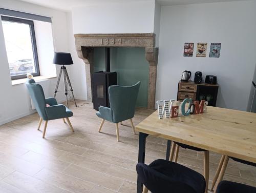 a living room with a table and chairs and a fireplace at Escapade bien-être avec Sauna et Balnéo - ChezBross' La Parenthèse in Aboën