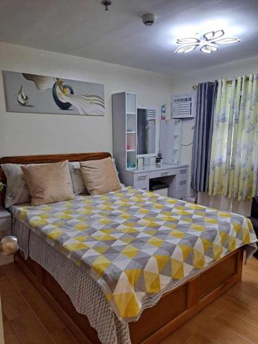 a bedroom with a large bed with a checkered blanket at Seawind Condominium Near Airport in Davao City