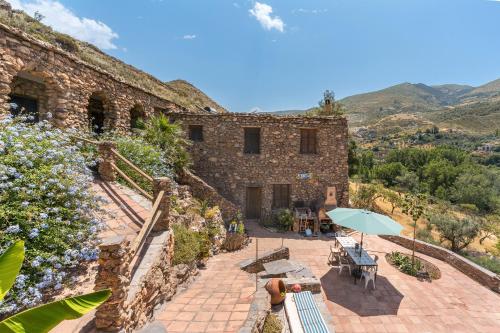 a stone building with a patio with an umbrella at Off-Grid - Puerto Mika in Órgiva