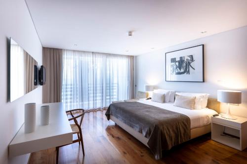 a hotel room with a large bed and a desk at Troia Design Hotel in Troia