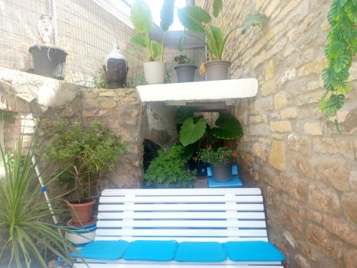 a white bench sitting next to a brick wall with plants at Cal Hidalgo in Palouet