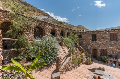 an old brick building with flowers on the side at Off-Grid - Puerto Mika in Órgiva