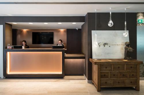 a lobby with two people sitting at a reception desk at Catalonia Magdalenes in Barcelona