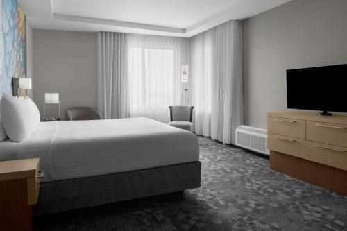 a hotel room with a bed and a flat screen tv at Courtyard by Marriott Houston Katy Mills in Katy