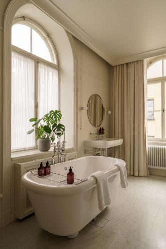 a white bathroom with a tub and a window at Stockholm Stadshotell in Stockholm