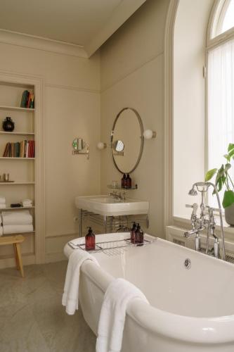 a bathroom with a tub and a sink and a mirror at Stockholm Stadshotell in Stockholm
