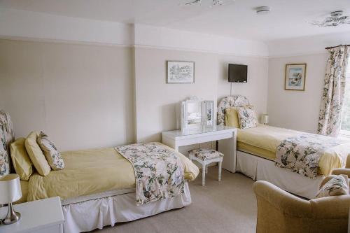 a bedroom with two beds and a desk and a chair at Leygreen Farmhouse B&B in Beaulieu
