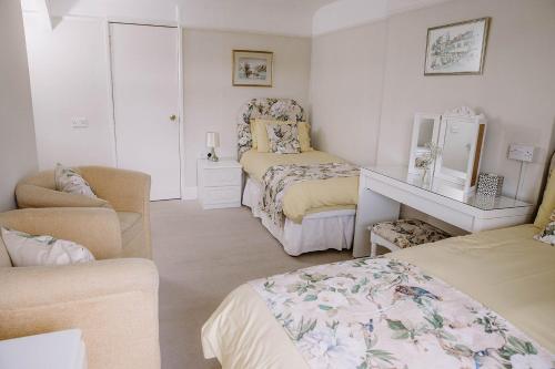 a bedroom with two beds and a chair and a mirror at Leygreen Farmhouse B&B in Beaulieu