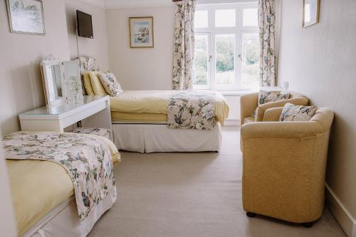 a bedroom with two beds and a couch and a chair at Leygreen Farmhouse B&B in Beaulieu