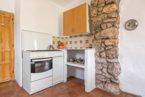 a kitchen with a white stove top oven next to a stone wall at Off-Grid - Puerto Mika in Órgiva