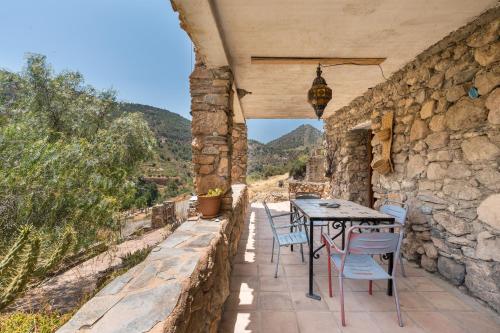 a patio with a table and chairs on a stone wall at Off-Grid - Puerto Mika in Órgiva