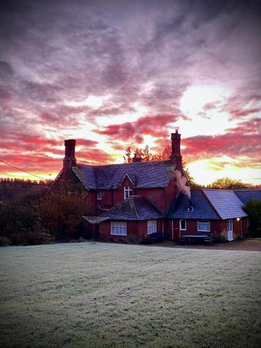 a large house with a sunset in the background at Leygreen Farmhouse B&B in Beaulieu