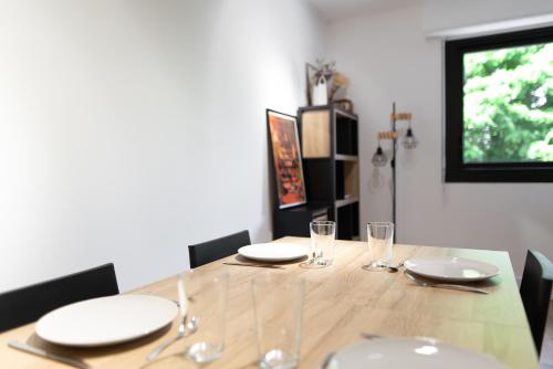 a dining room table with white plates and glasses at T2 - Havre paix 1à4p - Ramonville, Toulouse - Px Paul Sab & Labège - PKG in Ramonville-Saint-Agne