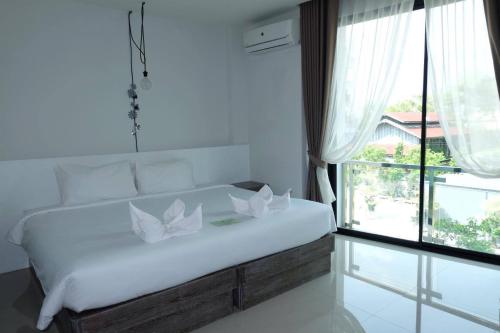 a bedroom with a bed with white pillows and a window at Hotel Chuan Chom The High Resort Saraburi - SHA Plus in Sara Buri