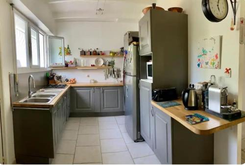 une cuisine avec un évier et un réfrigérateur dans l'établissement Villa plein pieds 8 personne piscine reste semaine juillet août, à Simiane-Collongue