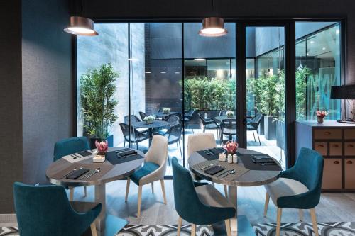 a restaurant with tables and chairs and windows at Catalonia Magdalenes in Barcelona