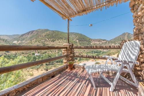 a rocking chair on a porch with a view of mountains at Off-Grid - Puerto Mika in Órgiva