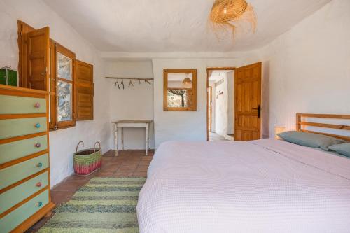 a bedroom with a white bed and a dresser at Off-Grid - Puerto Mika in Órgiva