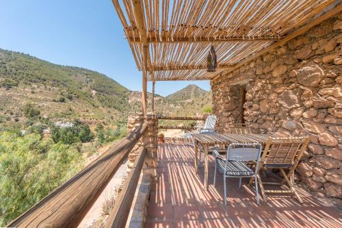 a wooden table and chairs on a deck with mountains at Off-Grid - Puerto Mika in Órgiva